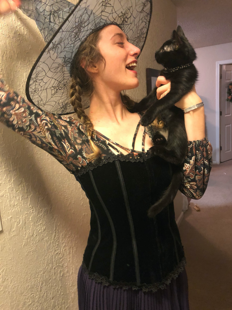 Woman in a Witch Costume Holding a Black Cat